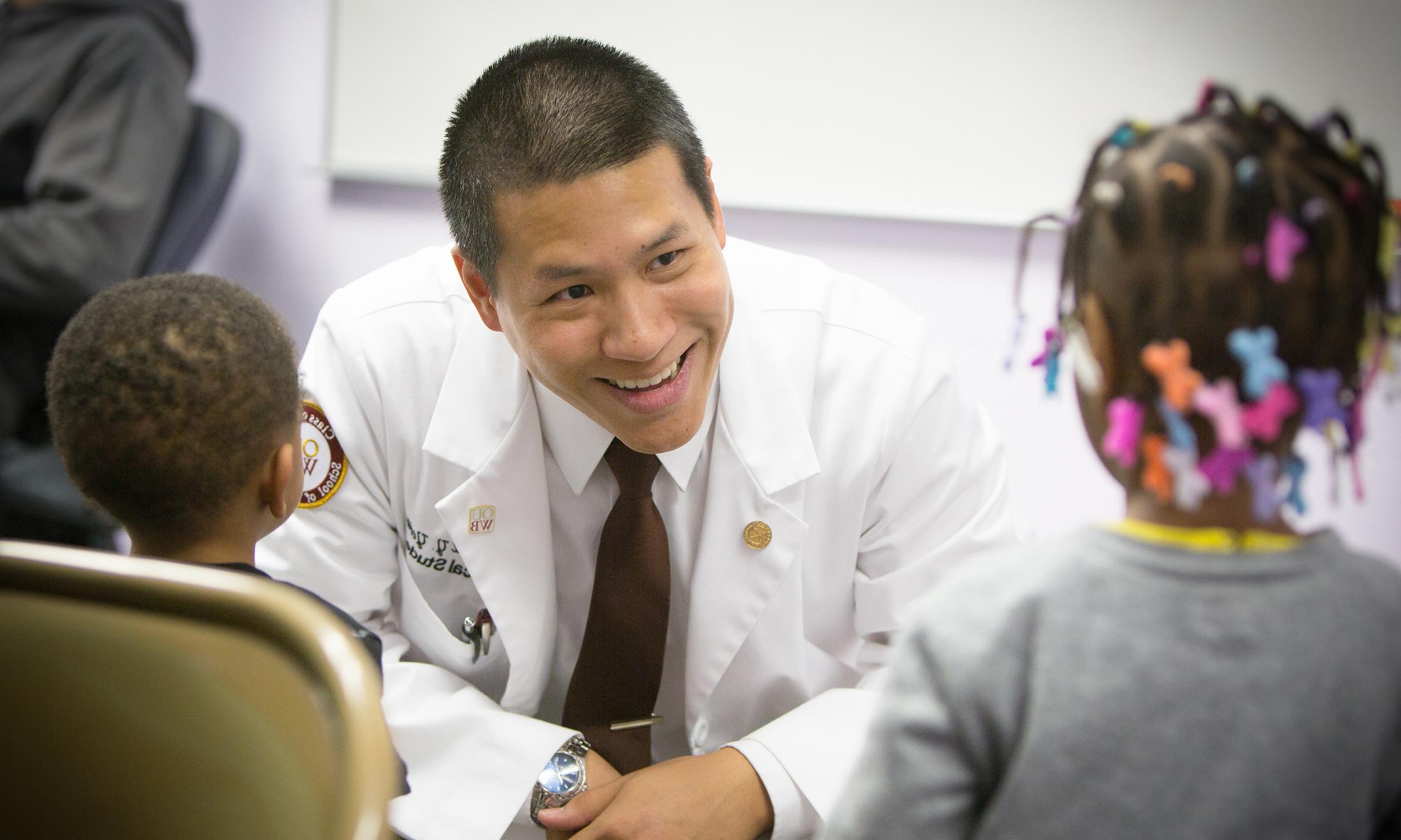 An image of Raymond Yeow, M.D., talking with children.